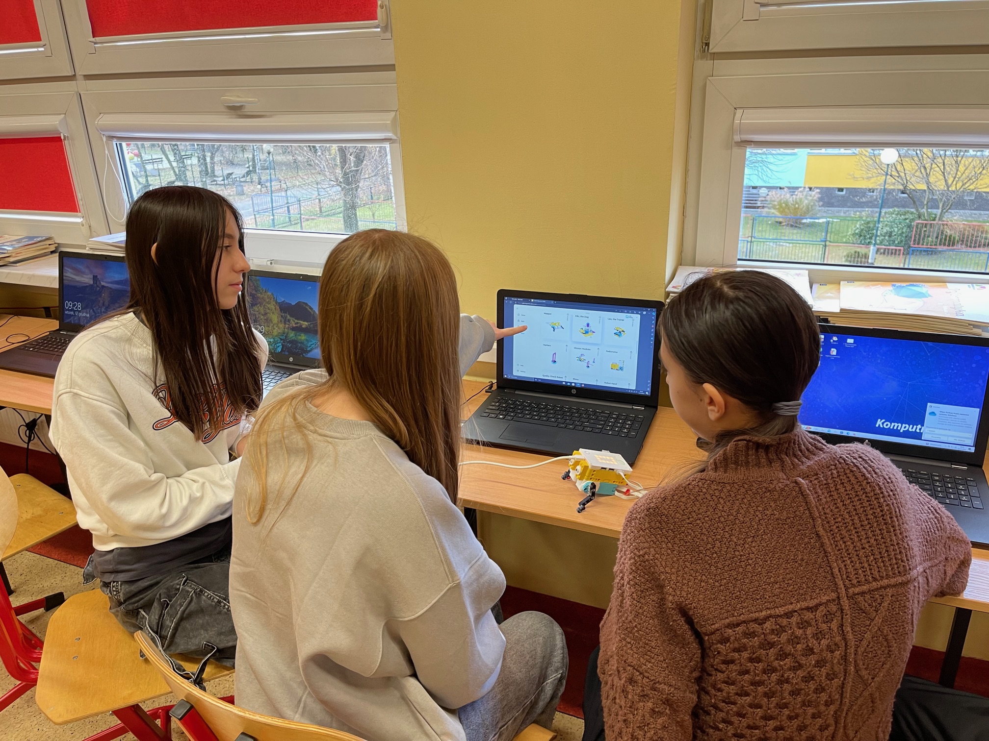 uczennice 7 c siedzą przy laptopie programują robota